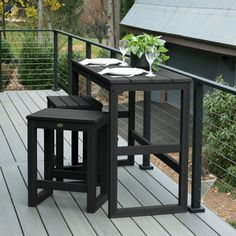 two black tables on a deck with plants