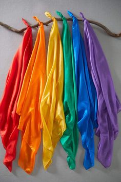 five different colored scarves hanging from a tree branch