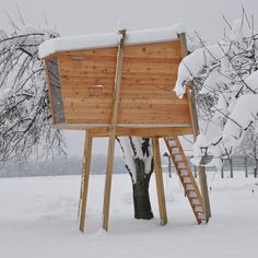 a wooden structure in the middle of a snowy field