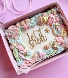 a cake in a pink box with the word hello written on it, surrounded by pastel decorations