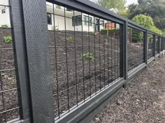 a black fence with metal bars on the top and bottom, in front of a house