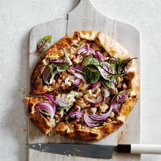 a pizza sitting on top of a cutting board next to a knife