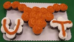 cupcakes with orange icing and white frosting in the shape of a texas logo