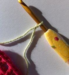 a crochet hook with yarn next to it on top of a white surface