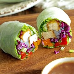 two wraps with lettuce, carrots and other vegetables on a cutting board