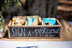 a sign that says sign a postcard with love is sitting on top of a table