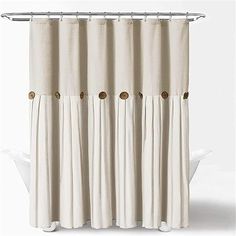 a white shower curtain with gold buttons on the top and bottom, hanging from a metal rod