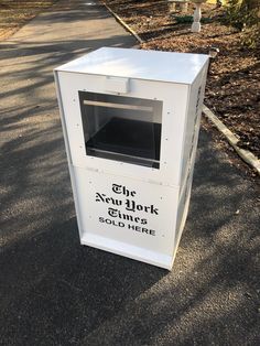 a white box sitting on the side of a road