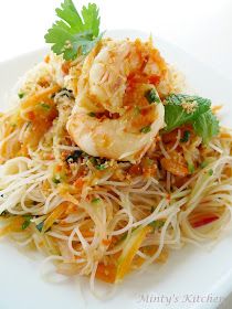 a white plate topped with pasta and shrimp next to parsley on top of it