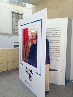 a woman standing in front of a white box with a photo on it and another person behind it