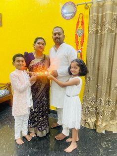 a family poses for a photo in front of a bright yellow wall with decorations on it