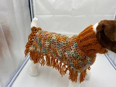 a stuffed dog wearing a sweater with fringes