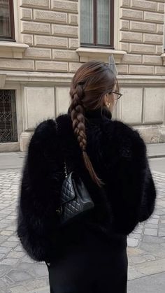 a woman walking down the street with her hair in a fishtail braid and black pants