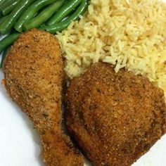 two pieces of chicken, rice and green beans on a plate