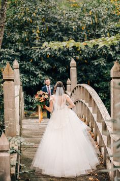 a bride and groom walking across a bridge