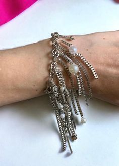 Fringed Chain Bracelet ⛓️ This stunning bracelet features a unique design that combines silver chains in different mediums with faux pearls. The result is a piece of jewelry that is both eye-catching and elegant. ⛓️ The bracelet is made with a variety of silver chains, including delicate curb chains and bolder link chains. The chains are fringed, creating a sense of movement and dimension. The faux pearls are interspersed throughout the chains, adding a touch of luxury and glamour. ⛓️ Only one a Metal Pearl Bracelet With Adjustable Chain, Metal Charm Bracelet With Pearl Chain, Adjustable Metal Pearl Chain Bracelet, Silver Metal Pearl Bracelet With Chain, Party Chain Bracelet In Metal, Silver Metal Pearl Bracelet With Adjustable Chain, Silver Metal Chain Bracelet For Party, Metal Chain Charm Bracelet, Metal Charm Bracelet With Adjustable Chain For Party