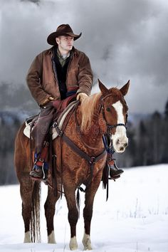 a man riding on the back of a brown and white horse in snow covered field