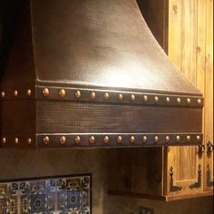 a large metal stove top mounted to the side of a wooden cabinet in a kitchen