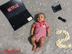 a baby laying on the ground next to a laptop