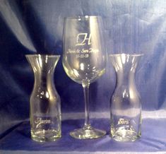 three wine glasses and one vase on a purple cloth