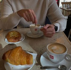 a man sitting at a table with coffee and croissants