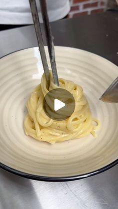 a plate with some noodles on it and a knife in the middle, being held by someone