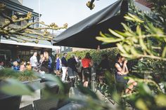 a group of people standing around in an outdoor area with trees and plants on either side of the building