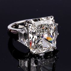 a fancy diamond ring on a black surface with reflective light reflecting off it's side