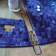 a piece of blue tile sitting on top of a wooden table next to a paint can