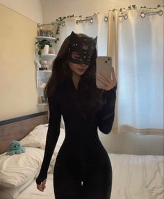 a woman in a black cat mask is taking a selfie