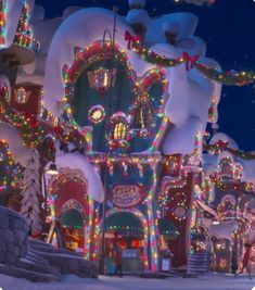 a christmas village with lights and decorations on it's roof, in the snow