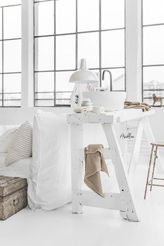 a white table topped with lots of pillows next to a window