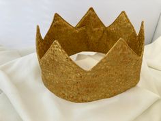 An adjustable crown made with Gold cotton metallic fabric. This crown is comfortably padded and easily washable.  Good for singling out the birthday person or celebrating the upcoming coronation.  Easily applied with Velcro Royal Gold Party Crown, Royal Gold Crown For Parties, Royal Gold Crown With Pinched Shape, Royal Gold Crown With Tall Shape, Royal Gold Tall Crown, Royal Teardrop Crown For Party, Adjustable Pinched Crown For Parties, Gold Tall Crown As Gift, Adjustable Tall Gold Crown