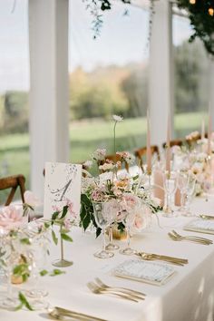 the table is set with place settings and flowers in vases on top of them