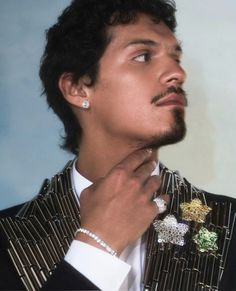 a man in a pinstripe suit adjusts his tie with an ornate brooch