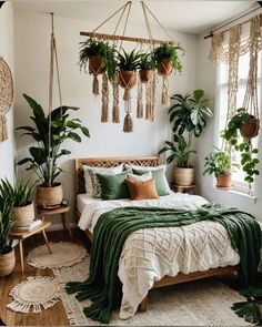 a bedroom with potted plants hanging from the ceiling and a bed covered in green blankets