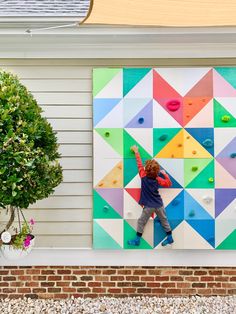 a young boy climbing up the side of a colorful wall