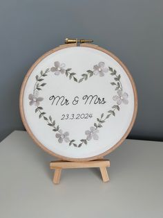 a personalized embroidered wedding ornament on a wooden easel with a white background