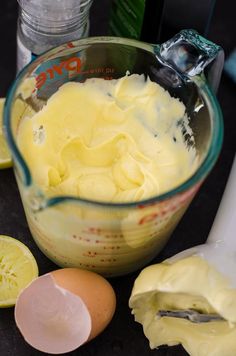 a bowl filled with yellow liquid next to sliced lemons and an egg yogurt