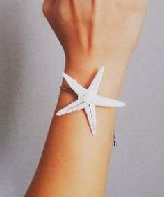 a woman's wrist with a white starfish bracelet on it