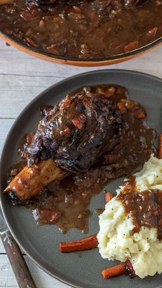 a plate with meat, mashed potatoes and gravy on it next to a skillet