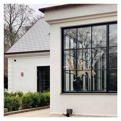 a white house with black windows and plants