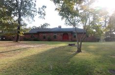 a red brick house sitting on top of a lush green field