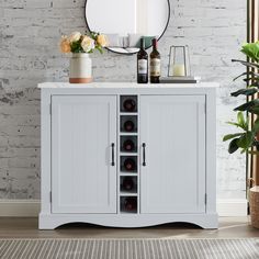 a white cabinet with wine bottles in it next to a mirror and potted plant