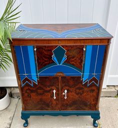 an art deco cabinet with blue and brown paint on it's doors, in front of a house