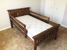 a bed frame made out of wood with no sheets on top and mattress in the middle