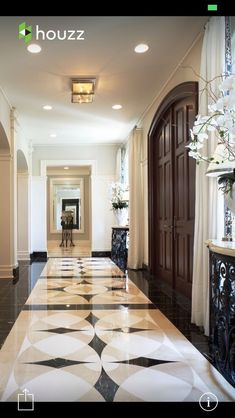 an elegant hallway with black and white tile flooring, chandelier and vases