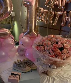 a bouquet of pink roses and balloons on a table in front of the number one balloon