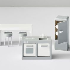 a toy kitchen set with stools, table and sink in white color on plain background