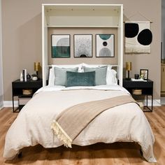 a bed with white linens and blue pillows in a room that has hardwood floors